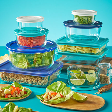 glass containers with various colored lids full of food on a blue background
