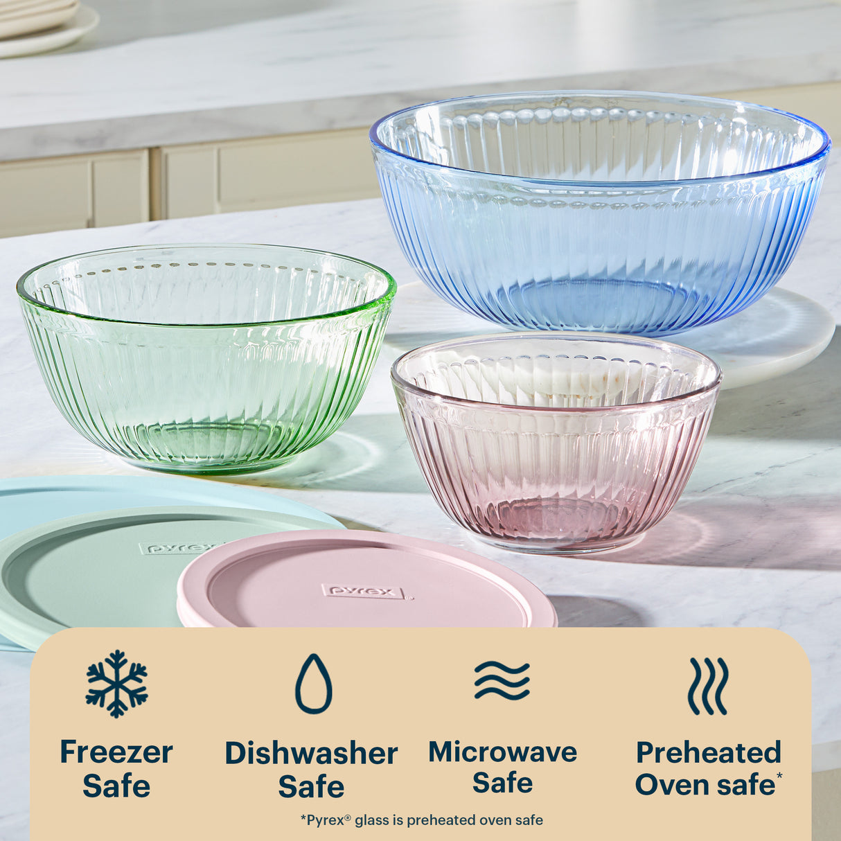 Set of three glass bowls in green, blue, and pink on a kitchen counter with Pyrex branding.