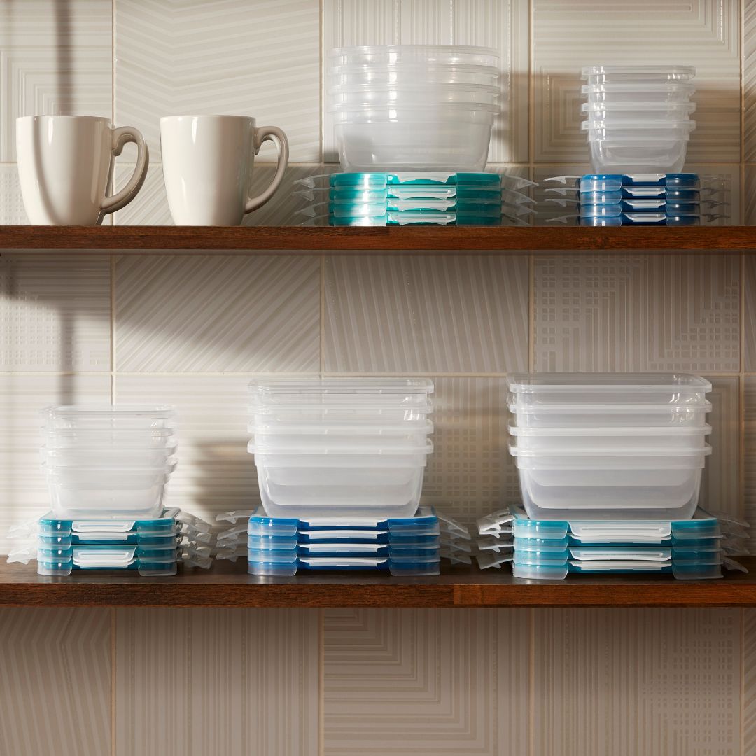 Stacks of plastic containers and mugs on a kitchen shelf against a tiled wall.